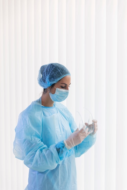 Médica mulher segurando óculos de proteção