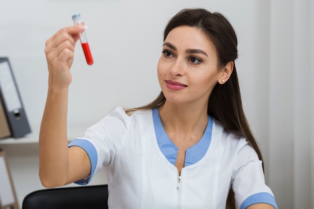 Médica, olhando para uma amostra de sangue