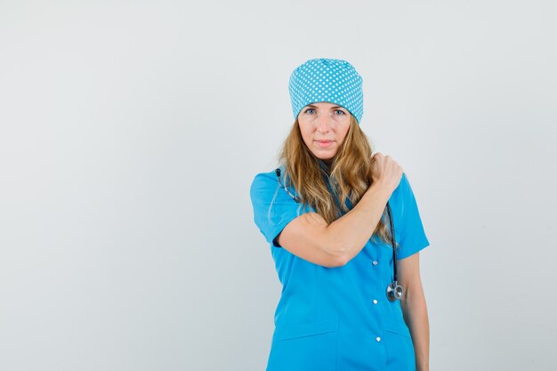 Médica segurando a mão na dor no ombro com uniforme azul
