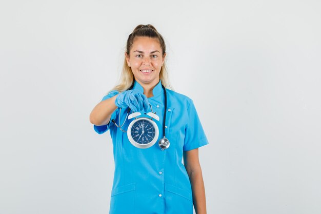 Médica segurando despertador em uniforme azul