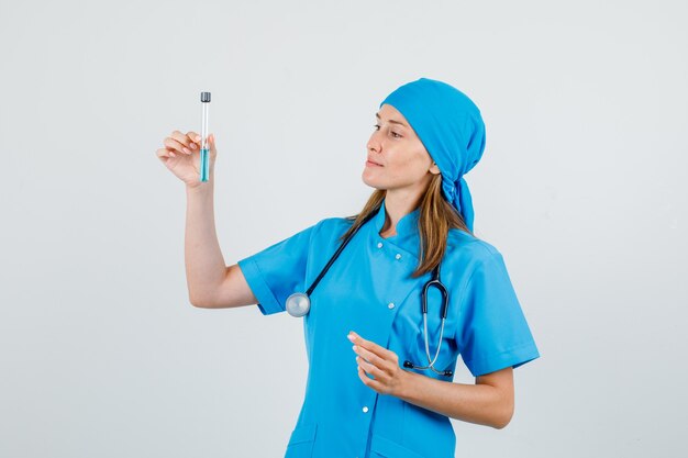 Médica segurando tubo de ensaio e sorrindo em vista frontal uniforme.