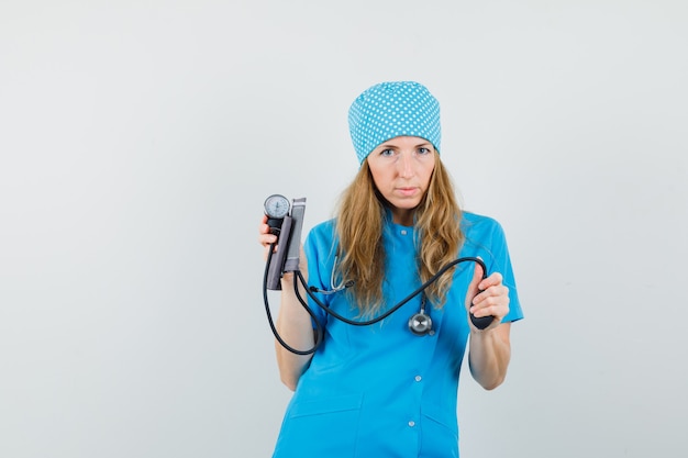 Médica segurando uma braçadeira de pressão arterial em uniforme azul