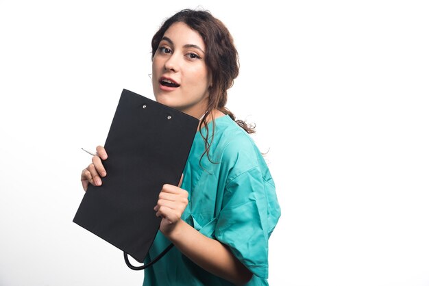 Médica segurando uma prancheta preta nas mãos, sobre fundo branco. Foto de alta qualidade