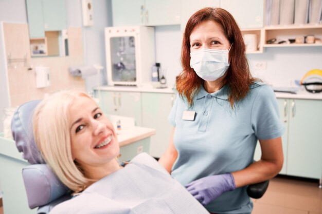 Médica sentada ao lado do paciente no consultório odontológico