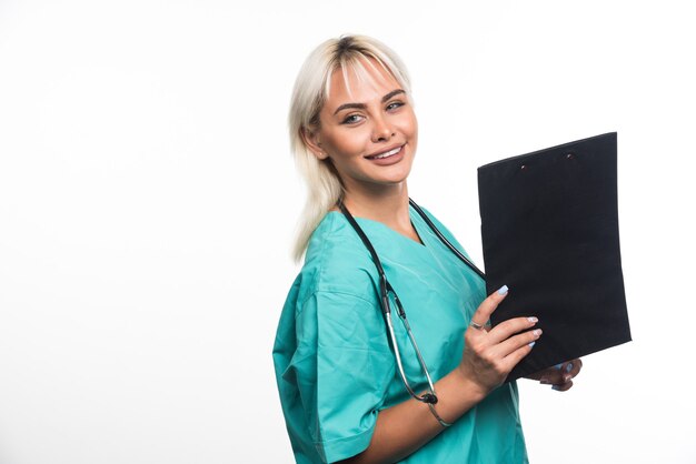 Médica sorridente segurando uma prancheta no fundo branco. Foto de alta qualidade