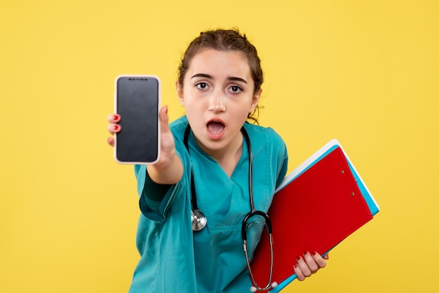 Médica vista frontal com camisa médica com anotações e telefone, vírus covid-19 pandêmico de uniforme emocional de saúde