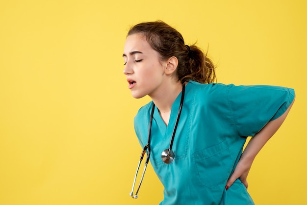 Médica vista frontal com camisa médica e dor nas costas, vírus da cor covid-19 uniforme saúde emoção