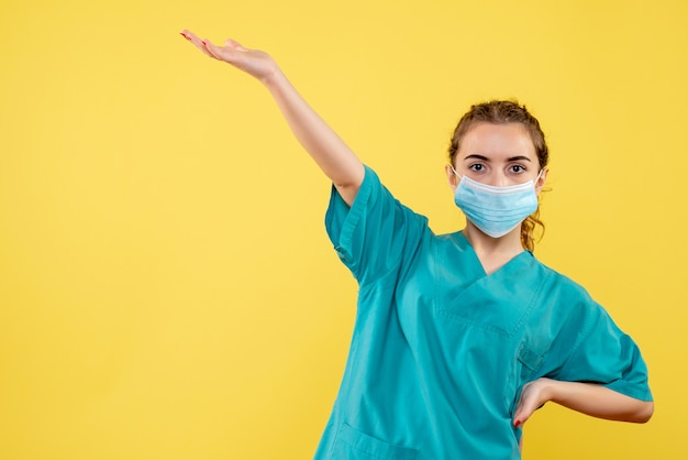Médica vista frontal com camisa médica e máscara estéril, cor uniforme do vírus da saúde covid-19 emoção