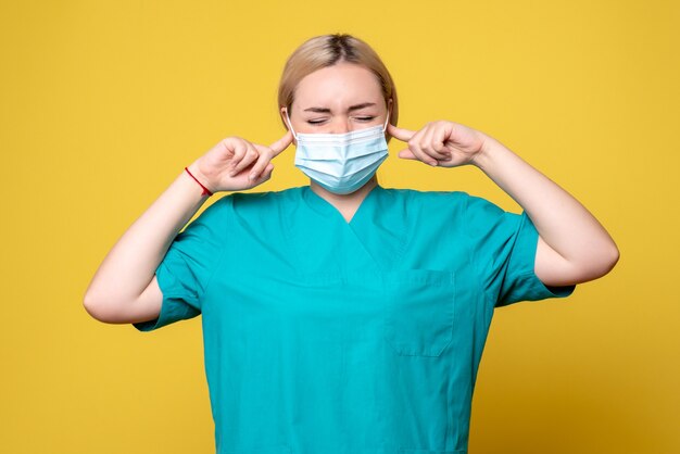 Médica vista frontal com camisa médica e máscara estéril tapando as orelhas