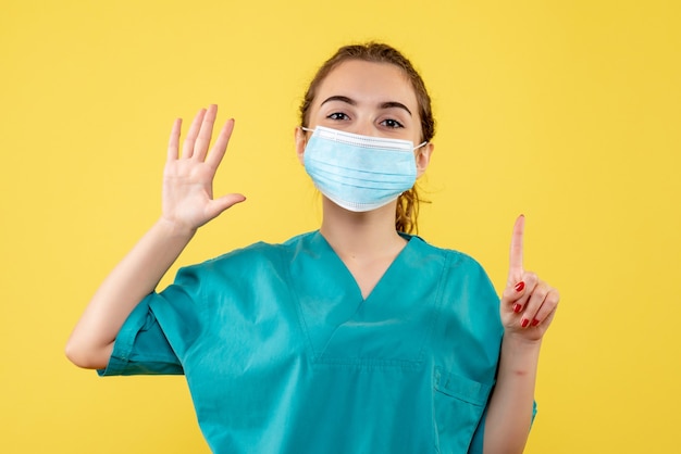 Médica vista frontal com camisa médica e máscara estéril, uniforme de vírus da saúde colorido covid-