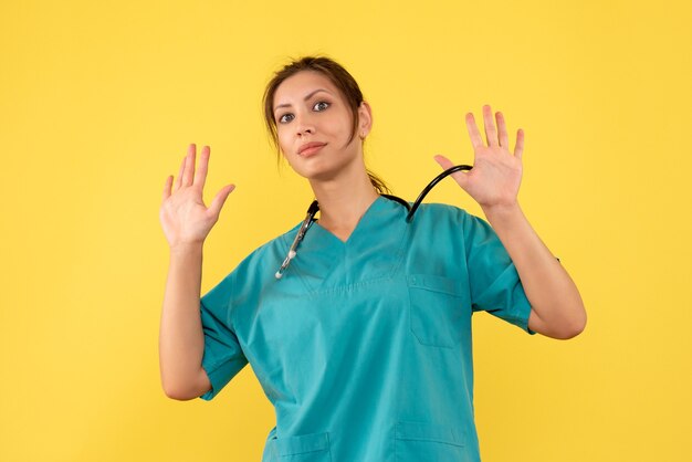 Médica vista frontal com camisa médica no fundo amarelo