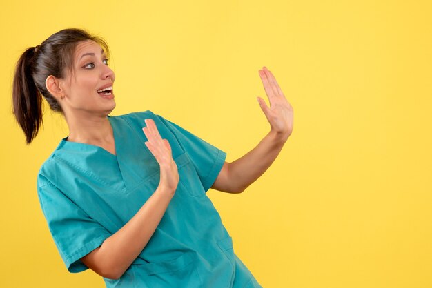 Médica vista frontal com camisa médica no fundo amarelo