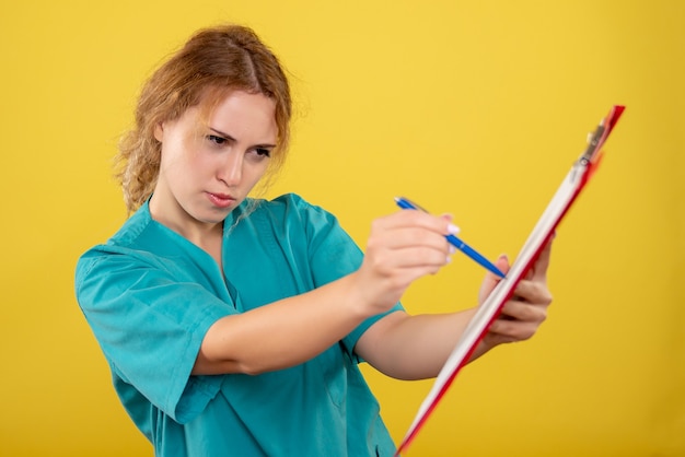 Médica vista frontal com camisa médica segurando análise, hospital cor covid-19 emoções de saúde