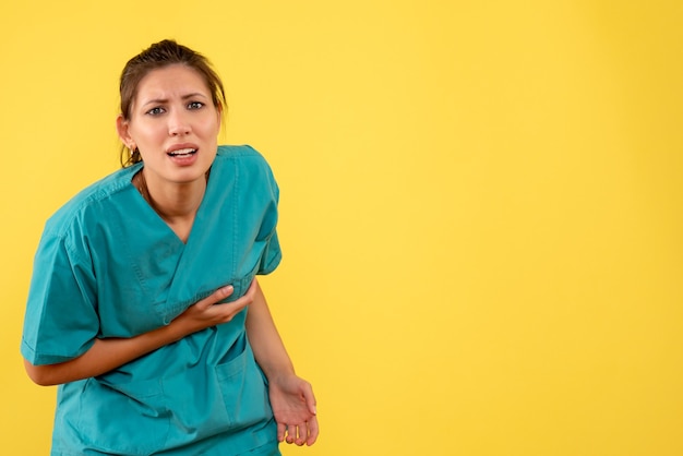 Foto grátis médica vista frontal com camisa médica sofrendo de dor de cabeça em fundo amarelo