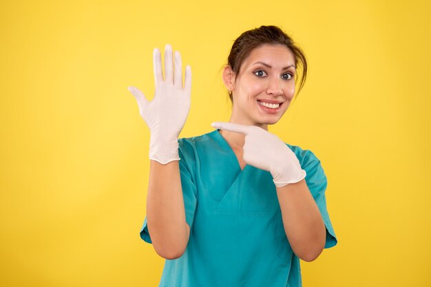 Médica vista frontal com luvas brancas em fundo amarelo