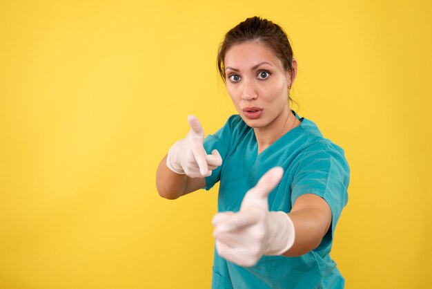 Médica vista frontal com luvas médicas em fundo amarelo