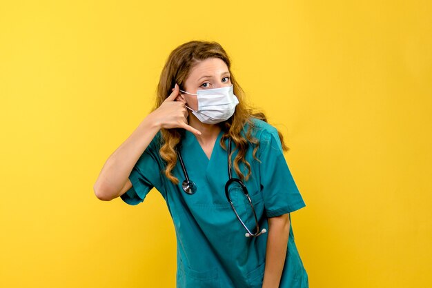 Médica vista frontal com máscara em um espaço amarelo