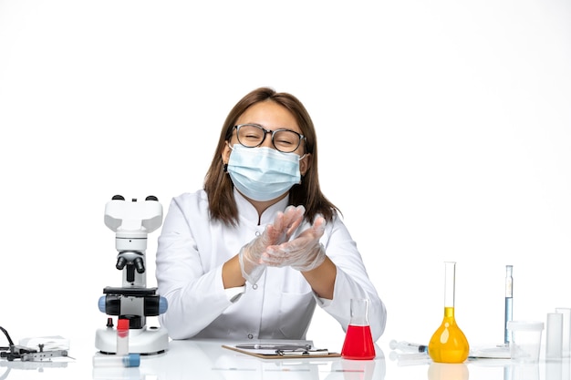 Médica vista frontal em traje médico com máscara devido ao cobiçado sorrindo em um espaço em branco