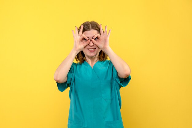 Médica vista frontal olhando por entre os dedos no espaço amarelo