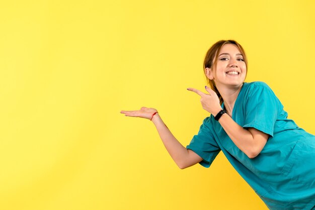 Médica vista frontal sorrindo no espaço amarelo