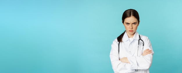 Foto grátis médica zangada trabalhadora médica que parece ofendida com os braços cruzados no peito franzindo a testa e olhando irritada