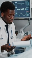 Médico americano africano consultando paciente com saco de gotejamento iv. médico de clínica geral verificando arquivos de exame para tratar a pessoa com doença, para curar com tratamento de prescrição e medicamentos