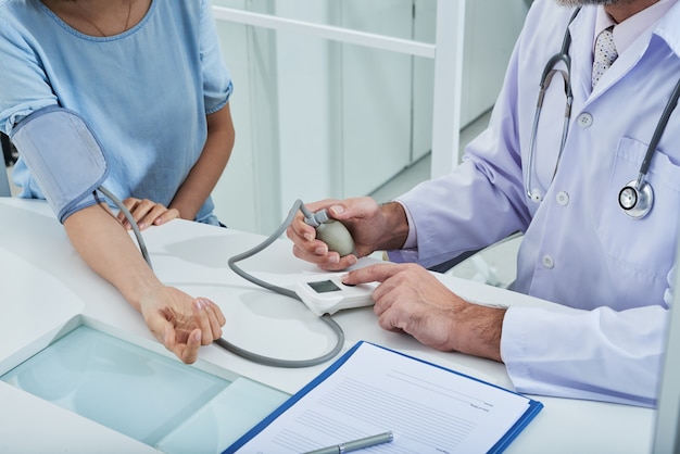 médico anônimo que mede a pressão arterial de um paciente irreconhecível com um tonômetro