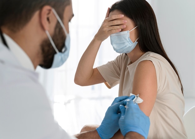 Médico aplicando vacina em paciente assustado