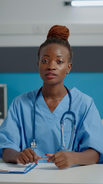 Médico assistente em videochamada remota para telemedicina usando tecnologia online enquanto está sentado no armário da mesa. Jovem enfermeira falando na internet conferência para aconselhamento e assistência