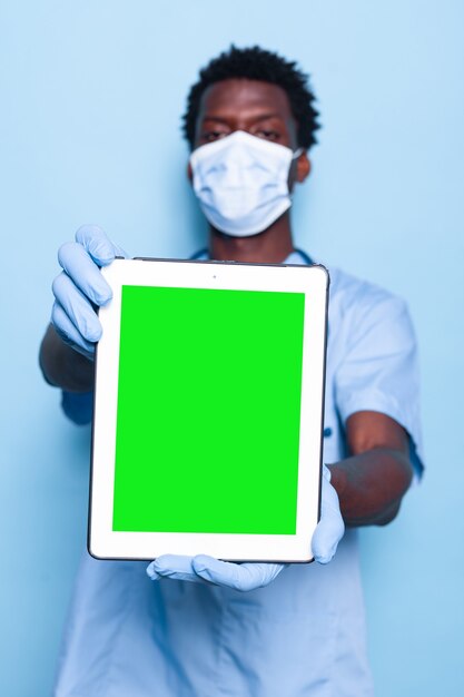 Médico assistente segurando uma tela verde vertical no tablet