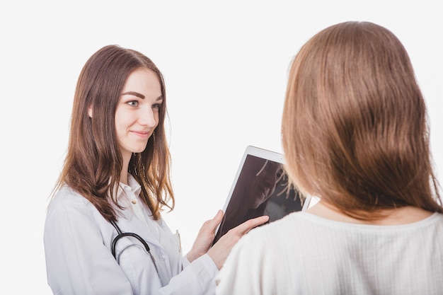 Médico bonito que mostra o comprimido ao paciente