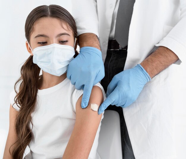Médico colocando um curativo no braço de uma menina