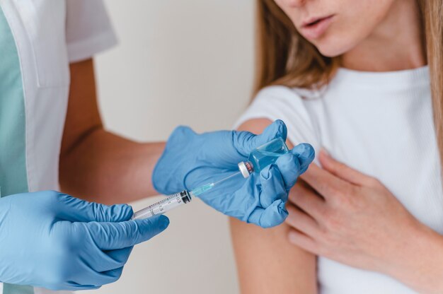Médico com luvas preparando vacina para uma mulher