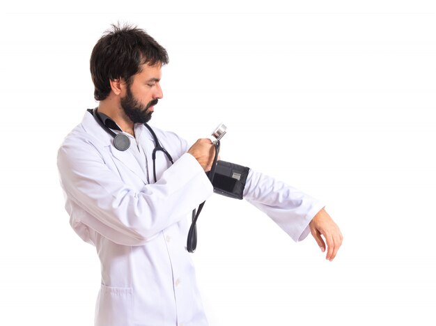Médico com monitor de pressão sanguínea sobre fundo branco