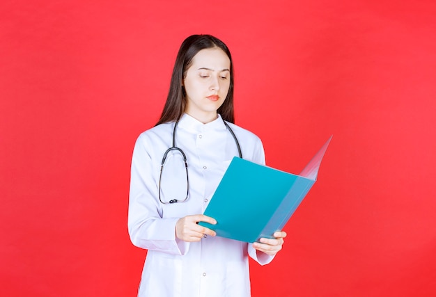 Médico com um estetoscópio segurando a história do paciente e verificando-a.