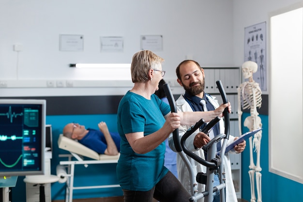 Médico conversando com paciente idoso fazendo exercícios físicos para se recuperar