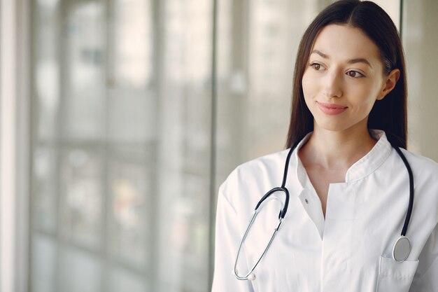 Médico da mulher em um uniforme branco em pé em um corredor