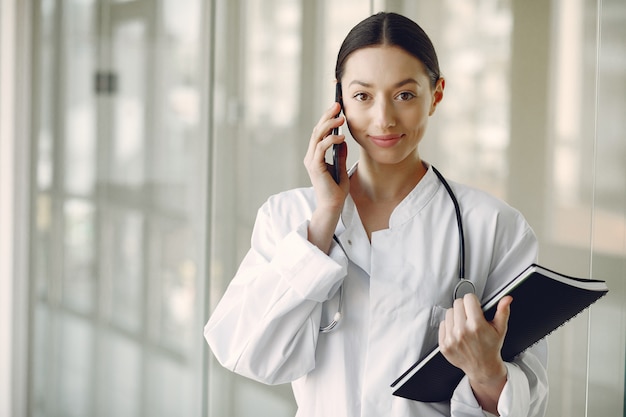 Médico da mulher em um uniforme branco em pé em um corredor