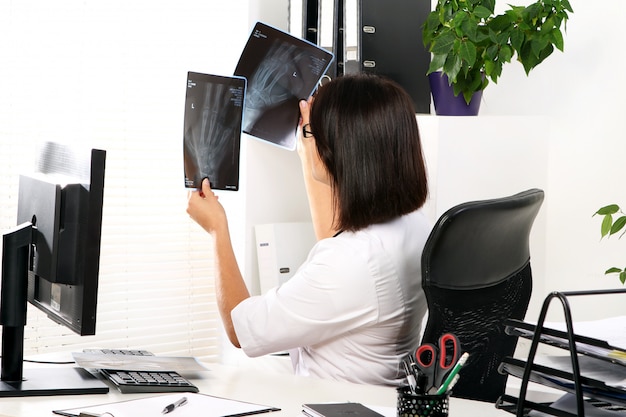 Médico da mulher está olhando o raio x da mão quebrada Foto gratuita