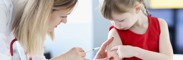 Médico dá um tiro de menina no ombro. conceito de vacinação infantil