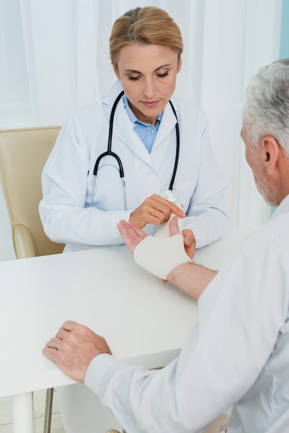 Médico de alto ângulo enfaixando a mão do paciente