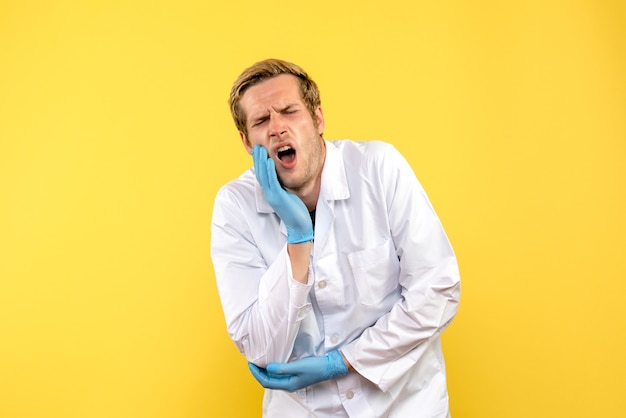 Médico de frente machucando o braço em fundo amarelo médico humano pandêmico covid