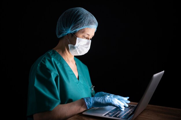 Médico de tiro médio com laptop e máscara