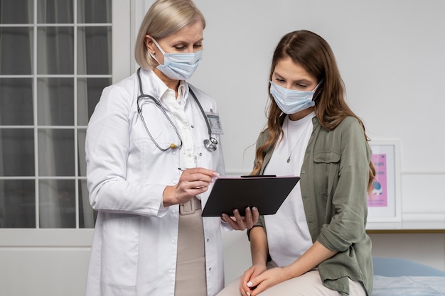 Médico de tiro médio e paciente usando máscaras