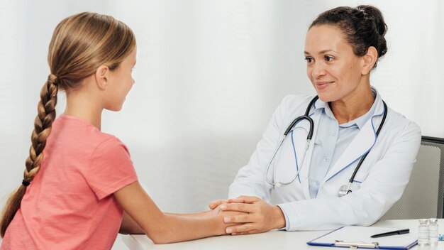 Médico de tiro médio falando com criança