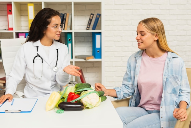 Médico de tiro médio falando com o paciente sobre legumes