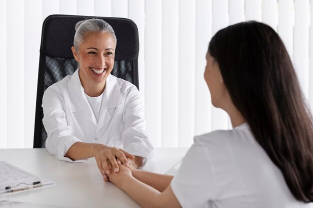 Médico de tiro médio segurando as mãos do paciente