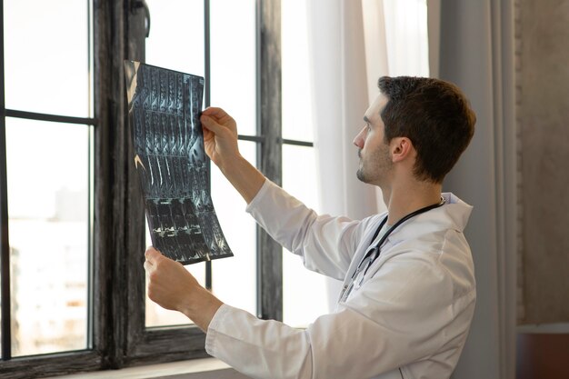 Médico de tiro médio segurando uma radiografia
