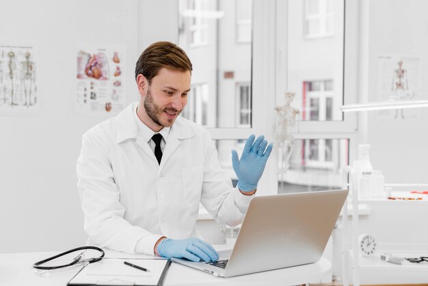 Médico de tiro médio trabalhando em um laptop