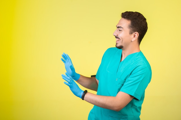 Médico de uniforme e máscara de mão impedindo algo ou alguém.